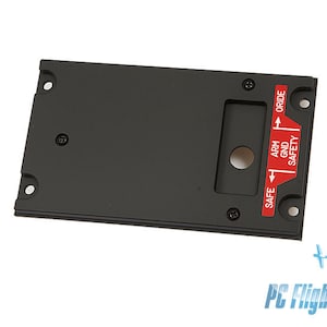 May include: Black aircraft panel with a red and white label that reads "SAFE ARM GND SAFETY ORIDE".