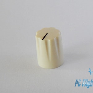 May include: A white plastic knob with a black line on the top. The knob has a ribbed design.
