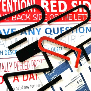 May include: Close-up of black and red letter stickers with the text "ATTENTION! RED SIDE IS THE BACK SIDE OF THE LETTERS HAVE ANY QUESTIONS? READ INCLUDED INSTRUCTIONS WHICH DESCRIBE ALL QUESTIONS PARTIALLY PEELED PROTECT NO A DAT"