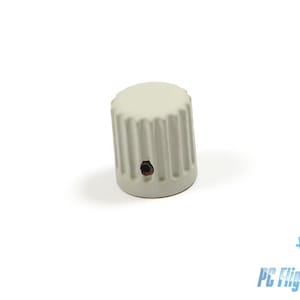 Puede incluir: Una perilla de plástico blanco con un diseño acanalado. La perilla tiene un pequeño agujero en el centro.