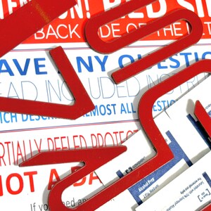 May include: Red plastic letters spelling out "HAVE ANY QUESTIONS" on a white background with blue text. The letters are partially covering the text, which reads "READ INCLUDED INSTRUCTIONS WHICH DESCRIBE ALMOST ALL QUESTIONS PARTIALLY DEFEATED PROTECT NOT A"
