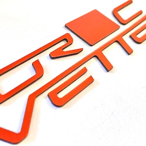 May include: A red metal car emblem with the word "Vtec" in a stylized font.