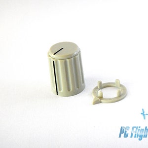 May include: A beige plastic knob with a black line down the center and a separate beige plastic ring with three prongs.