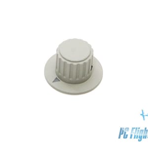 May include: A white plastic knob with a small triangle on the front. The knob has a ridged edge and a smooth, round top.