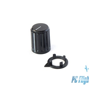 May include: Black plastic knob with a white line on the top and a black plastic ring. The knob is used for controlling electronic devices.