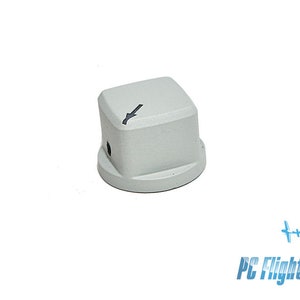 Op de afbeelding: Een grijze plastic knop met een zwarte pijl die naar links wijst. De knop heeft een klein gaatje in het midden.