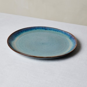May include: A blue and brown ceramic dinner plate with a reactive glaze.