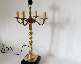 Puede incluir: Una lámpara de mesa de candelabro dorada con cinco portavelas y una base cuadrada negra.