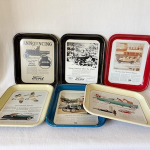 May include: Five vintage metal trays with colorful borders and advertisements for Ford and Lincoln cars. The trays feature black and white images of cars and text that reads "Announcing", "Young America takes the wheel", "The New Ford Station Wagon", "Southward Flight", and "A Riding Ford Roadster".