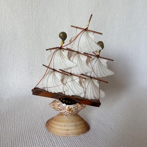 May include: A white ceramic mug with a black handle and the text "But First, Coffee" in a bold, black font. The mug is set against a blurred background, suggesting a cozy setting. The mug appears to be approximately 4 inches tall.