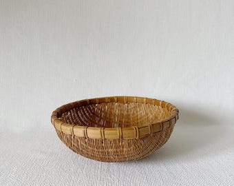 Cesta redonda de ratán tejido vintage, ideal para guardar frutas, estilo bohemio, cocina rústica o casa de campo.