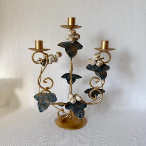 Vintage gold metal candelabra with green leaves and cream wooden berries, three-arm candle holder, romantic Italian-style home decor.