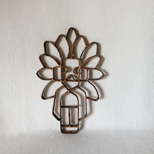 May include: A cutout wooden wall decor in the shape of a Native American figure with a headdress. The figure is brown and has a simple design.