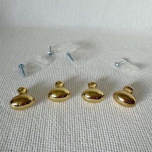 May include: Four gold oval cabinet knobs with a shiny finish. Each knob comes with a screw for installation.