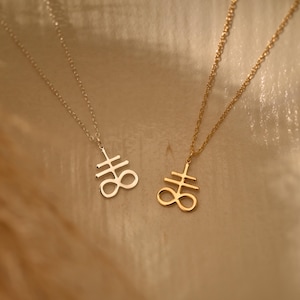 May include: Two necklaces with a silver and gold pendant featuring the sigil of the Leviathan. The sigil is a stylized cross with an infinity symbol.