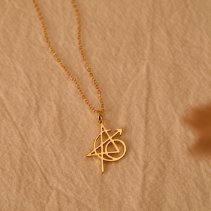 Può includere: Una collana color oro con una catenina sottile e un ciondolo a forma di logo degli Avengers. Il ciondolo è una lettera A stilizzata racchiusa in un cerchio, con una freccia che si estende sul lato destro, il tutto con una finitura dorata.
