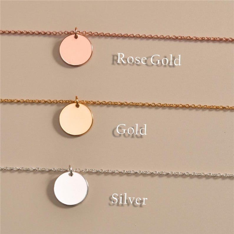 May include: Close-up of three necklaces in rose gold, gold, and silver. Each necklace features a delicate chain and a circular pendant. The words "Rose Gold", "Gold", and "Silver" are printed below each necklace.