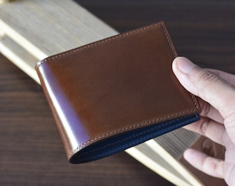 May include: A brown leather wallet with a blue stitched edge. The wallet is closed and has a smooth, glossy finish.