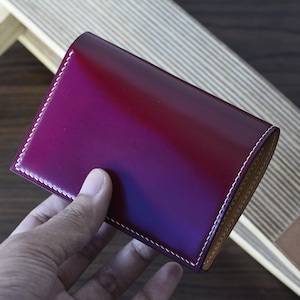 Cartera plegable vertical de piel cordobesa roja con concha de granate y buttero italiano natural.