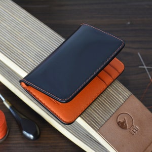 Tarjetero plegable de 8 bolsillos en piel de cordero negra y buttero italiana naranja. Cartera vertical minimalista. Cartera con bolsillo frontal.