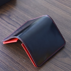 Cartera mediana de piel de cordero con concha negra y buttero rojo. Cartera de regalo para hombre.