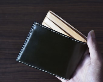 May include: A dark green leather wallet with white stitching, open to reveal a tan leather interior.