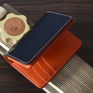 Cartera mediana de piel de cordero con concha negra y buttero naranja. Cartera de regalo para hombre.