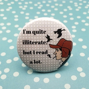 May include: A round button with the text "I'm quite illiterate, but I read a lot." The button features an illustration of a person in a red hat smoking a cigarette, with birds in flight. The background has a gray and white checkered pattern.