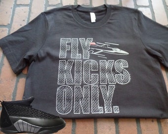 May include: A black t-shirt with a white graphic print that says "FLY KICKS ONLY." A black and grey shoe is in the foreground.