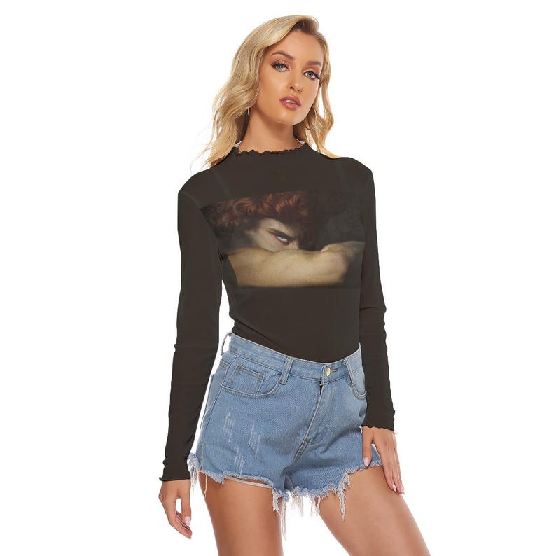 May include: Black long-sleeve shirt with a high ruffled neckline. The shirt features a rectangular print of a Renaissance-style painting. The model is wearing denim shorts. The shirt is made of a soft, comfortable material.