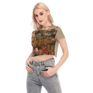 Puede incluir: Camiseta corta con estampado de pintura renacentista. La camiseta tiene mangas cortas y cuello alto. La obra de arte representa una escena detallada con numerosas figuras y una variedad de colores, incluyendo marrones, rojos y verdes.