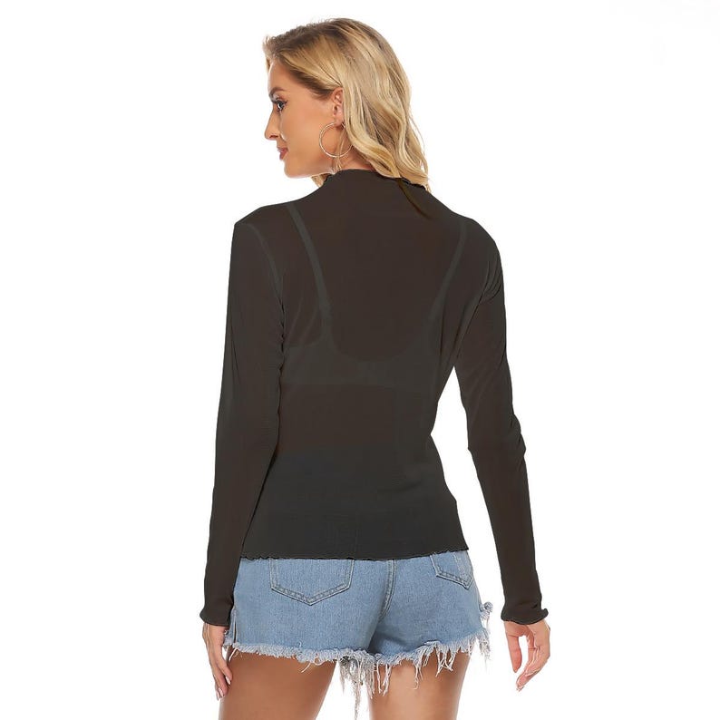 May include: A black, sheer long-sleeve top with a high neckline and a slightly ruffled hem. The top is paired with denim shorts. The model is wearing hoop earrings.