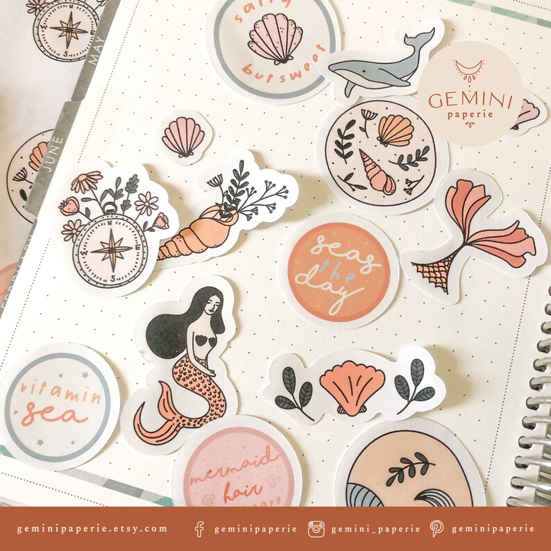 May include: A collection of stickers featuring a variety of ocean-themed illustrations, including seashells, mermaids, a compass, and the phrase "seas the day". The stickers are in a variety of colors, including pink, blue, and green. The stickers are perfect for adding a touch of whimsy to your planner, journal, or laptop.