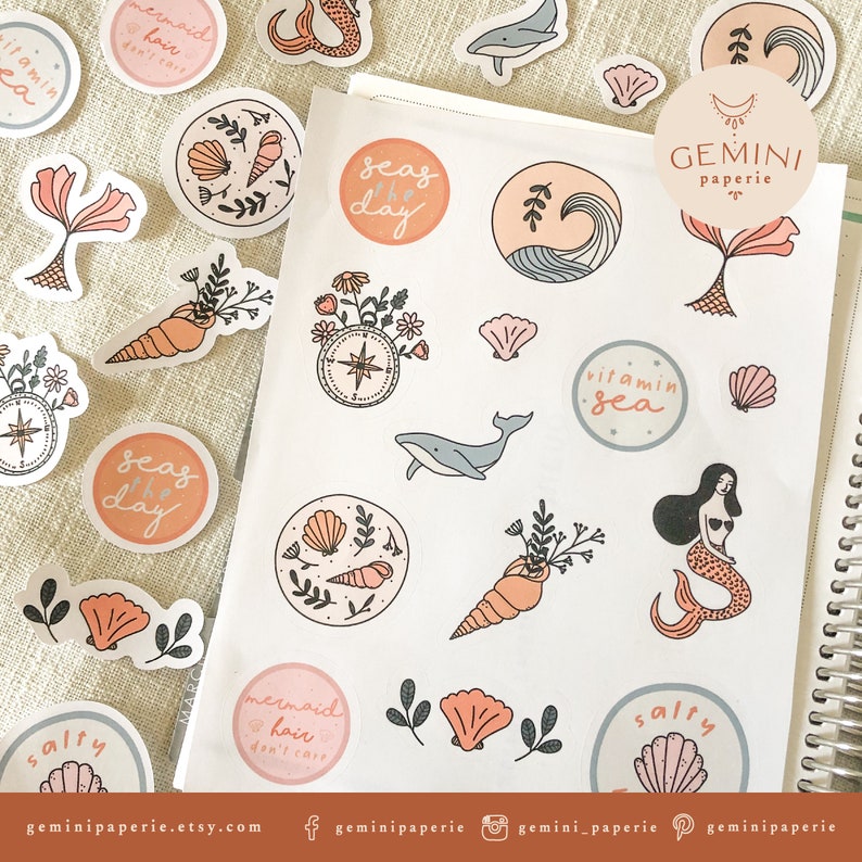 May include: A sheet of stickers with a sea theme. The stickers feature illustrations of seashells, mermaids, whales, and other ocean-related imagery. The stickers are in a variety of colors, including pink, blue, and green. The text "GEMINI paperie" is printed on one of the stickers.