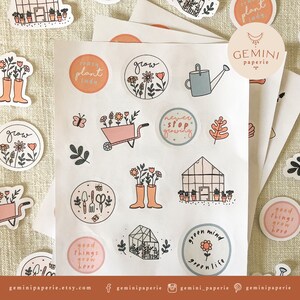 May include: A sheet of stickers with a gardening theme. The stickers are round and feature illustrations of plants, flowers, gardening tools, and text such as "grow", "crazy plant lady", "never stop growing", and "good things grow here".