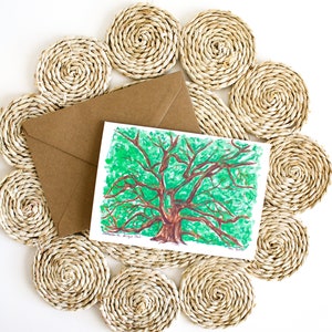 May include: A watercolor painting of a large, green tree with brown branches and trunk. The painting is on a white card with the text "Southern Live Oak" and "Van Scott" written in black ink. The card is on a woven straw mat.