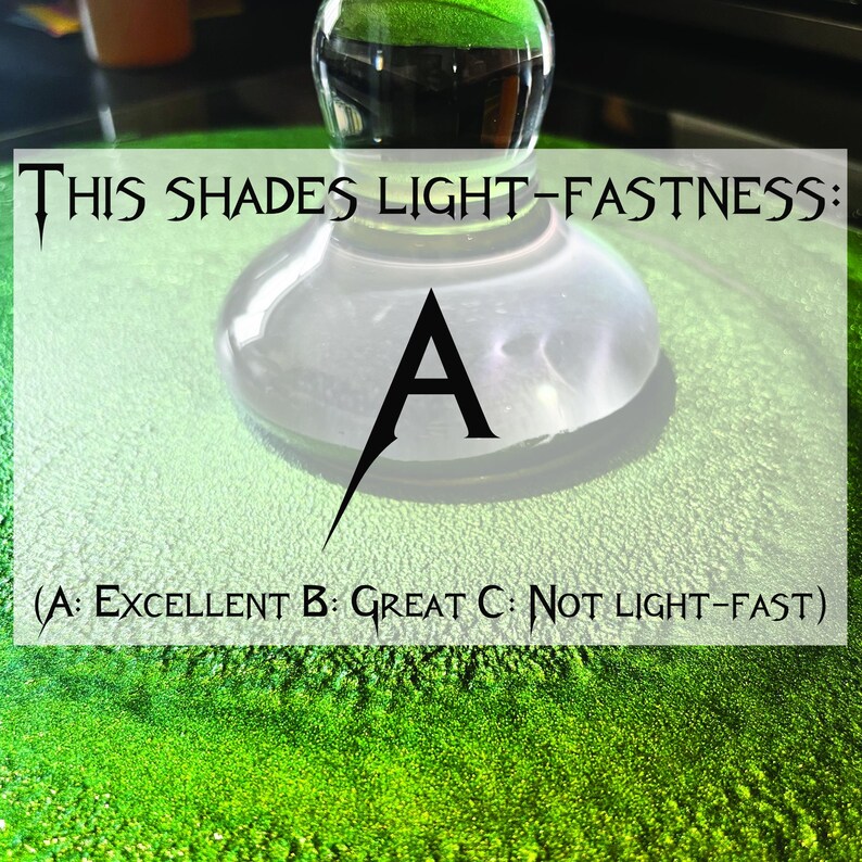 May include: A green surface with a glass object on top. The glass object has a white surface with the letter "A" printed on it. The text "THIS SHADES LIGHT-FASTNESS: (A: EXCELLENT B: GREAT C: NOT LIGHT-FAST)" is printed on the surface.