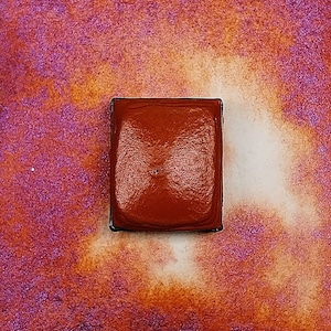 Könnte beinhalten: Eine einzelne Schale mit Aquarellfarbe in einem dunklen Braunton. Die Schale befindet sich in einem Metallgehäuse mit einem leicht erhöhten Rand.