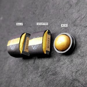 May include: Three different sizes of gold pigment in black containers labeled "Half", "Quarter", and "Mini". The containers are labeled "MIDAS" and have a gold stripe.