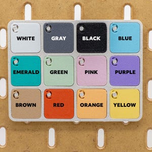 May include: A color palette with twelve square tiles, each labeled with a different color name: White, Gray, Black, Blue, Emerald, Green, Pink, Purple, Brown, Red, Orange, and Yellow. The tiles are arranged in a grid.