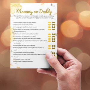 May include: A printable game card with a yellow and white honeycomb pattern and the text "Mommy or Daddy". The card has 14 questions about a new baby, with options for "Mommy" or "Daddy" to be circled.