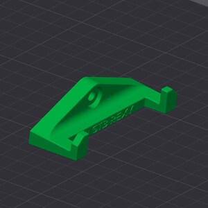 Op de afbeelding: Een heldergroen 3D-geprint object met een gebogen ontwerp, een cirkelvormig gat en een kleine rechthoekige uitsteeksel. De tekst "GTS REX" is zichtbaar aan de zijkant. Geplaatst tegen een donkergrijze rasterachtergrond.