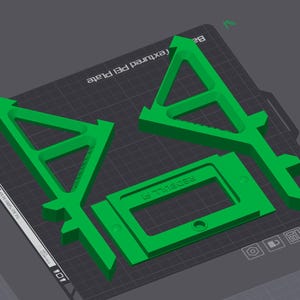 May include: Green 3D-printed parts, including two triangular shapes with arrow-like tops and a rectangular frame with the text "REDBULL F1". The parts are arranged on a textured surface.