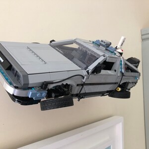 K&ouml;nnte beinhalten: Ein graues und silbernes Lego-Modell des DeLorean-Zeitfahrzeugs aus der Back-to-the-Future-Filmreihe. Das Modell schwebt in der Luft und die R&auml;der drehen sich.