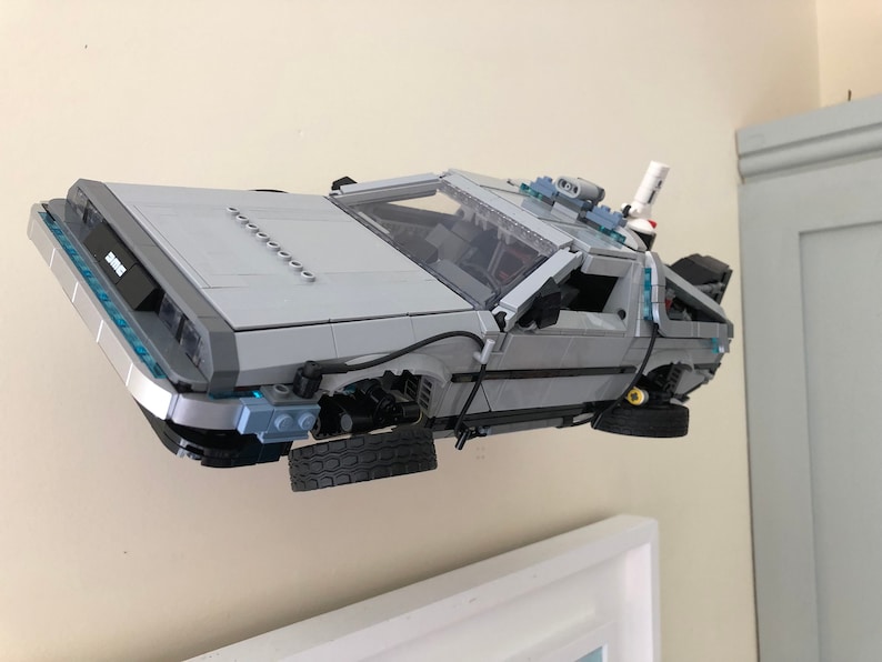 K&ouml;nnte beinhalten: Ein graues und silbernes Lego-Modell des DeLorean-Zeitfahrzeugs aus der Back-to-the-Future-Filmreihe. Das Modell schwebt in der Luft und die R&auml;der drehen sich.