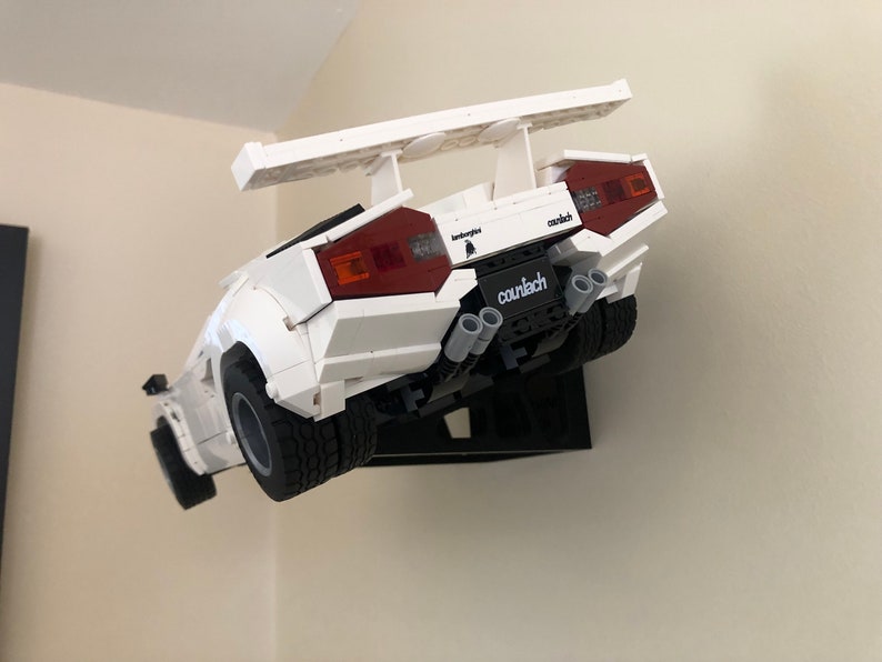 May include: A white Lego Lamborghini Countach model with a rear wing, red taillights, and the text "Lamborghini Countach" printed on the back.