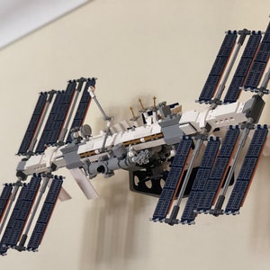 May include: A white and gray Lego model of the International Space Station with multiple solar panels.