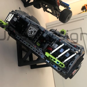 Pu&ograve; includere: Un'auto modello Lego nera e verde con un logo Peugeot bianco sul lato. L'auto &egrave; montata su un supporto da parete nero.