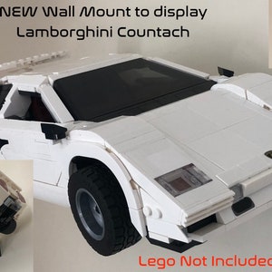 May include: A white Lego Lamborghini Countach model car mounted on a black wall mount. The mount is designed to display the car as if it is driving up a wall. The text "Lego Not Included" is printed below the car.