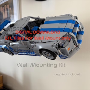 May include: A silver and blue model car, constructed from interlocking blocks, is displayed. The car is mounted on a wall, with the text "DIGITAL DOWNLOAD STL Files For Wall Mount only" and "Wall Mounting Kit" visible. The words "Lego Not Included" are also present.